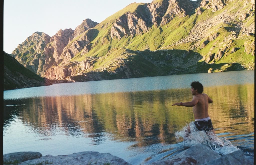 Alguien metiéndose a una laguna de montaña al atardecer